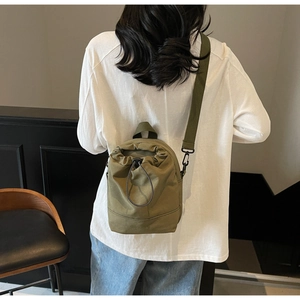 Olive green drawstring canvas phone bag with adjustable shoulder strap on a female model