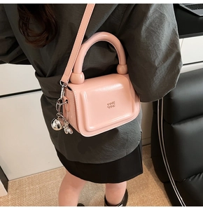 Détail du sac à main en cuir rose brillant avec breloque boule argentée et logo GOIH SDIN