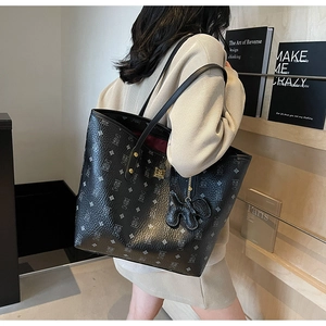 Detailed side view of black printed tote bag with bear motif and red interior lining