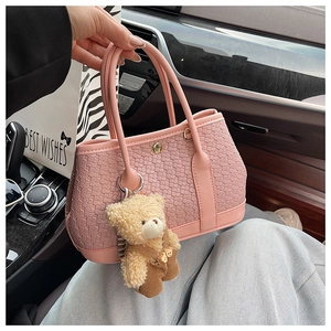Detail of pink woven leather bucket bag with a cute teddy bear charm and gold clasp