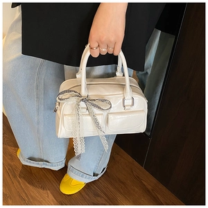 Détail d'un sac Boston blanc brillant avec ruban en dentelle et poches