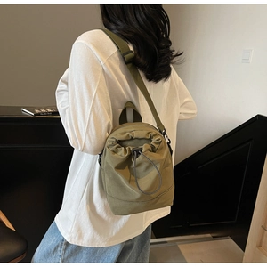 Detail of army green drawstring crossbody bag worn by model showing size and texture