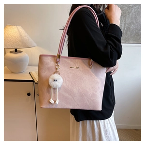 Detail of pink faux suede tote bag with plush charm accessory in a warm interior setting