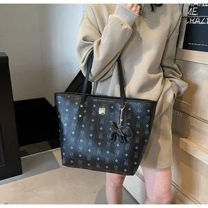 Close-up of printed tote bag with leather texture and bear charm on shoulder