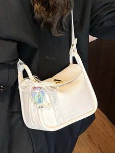White lychee leather shoulder bag with gold clasp and cute cartoon charm