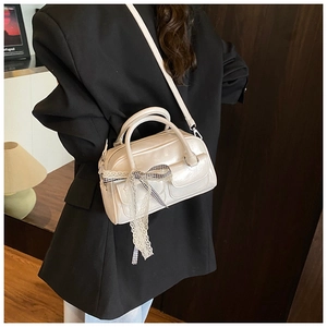 Détail du sac Boston blanc crème en similicuir avec nœud en dentelle et poignées