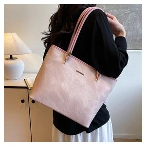 Detail of pink suede tote bag with golden metal bar decoration and long shoulder straps