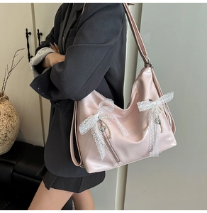 Detail of pink glossy shoulder bag with lace bow, pearl pendant and side zipper features