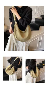 Detail of light green crescent canvas bag showing the wide strap and exterior front pocket