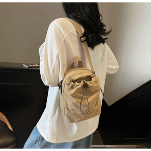 Close-up of khaki canvas drawstring crossbody bag showing texture and wide strap detail