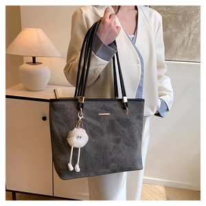 Detail of grey marble texture tote bag with plush doll charm and sleek black straps