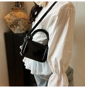 Détail d'un sac à main en cuir verni brillant avec poignée ronde et pendentif sphérique
