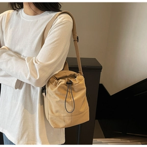 Close-up of beige drawstring bucket bag with high-density canvas texture and adjustable strap