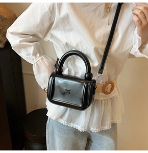 Détail du sac à main en cuir verni noir brillant avec lettres gaufrées et bijoux argentés