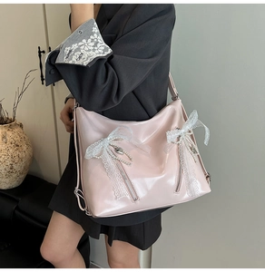 Detail of light pink patent leather tote bag with lace bows and pearl chain ornaments