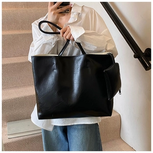 Detail of a large black soft leather tote bag with a small zippered pouch attachment