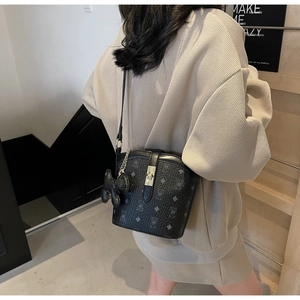 Classic black printed bucket bag with plush charm shown worn by a model in a casual setting