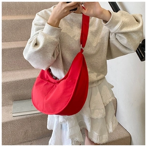 Close-up of red large Hobo crossbody bag with wide shoulder strap worn by a model