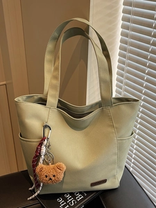 Minimalist light green canvas tote bag with plush bear pendant for students and daily commute