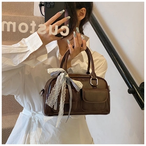 Détail du sac Boston marron foncé brillant avec nœud en dentelle et deux poches avant