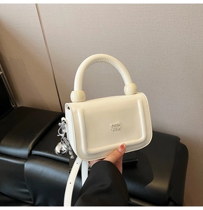 Détail d'un mini sac à main blanc cassé avec poignée épaisse et breloque ours argenté