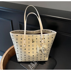 Close-up of beige tote bag with bear print, lychee leather texture, and cute charm