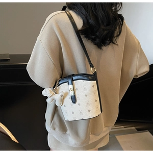 Detail of printed bucket bag with bear patterns, leather strap, and golden lock buckle