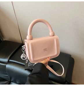 Détail d'un sac à main rose en cuir huilé avec poignée épaisse et breloque argentée