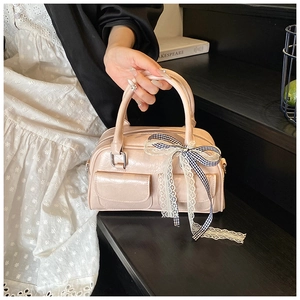 Détail du sac Boston rose brillant avec petites poches avant et décoration de nœud