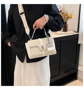 Detail der cremefarbenen gewebten Handtasche mit weißem Lederbesatz und breitem Gurt