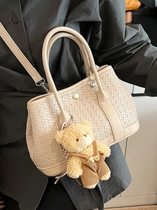 Minimalist woven bucket bag in beige with ring handles and a plush bear pendant accessory