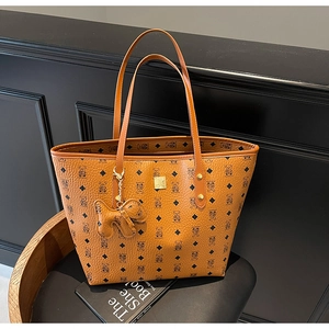 Close-up of yellow leather tote bag featuring bear monogram and gold metal logo plaque
