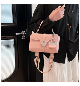 Detail der rosa geflochtenen Tasche mit besticktem Gurt und Metall-Drehverschluss