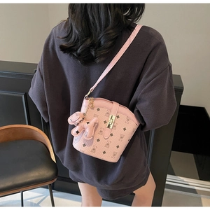 Detail of pink bucket bag with bear patterns, gold buckle and bear keychain accessory