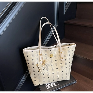 Detail of light beige tote bag with bear print pattern and cute bear shaped leather charm