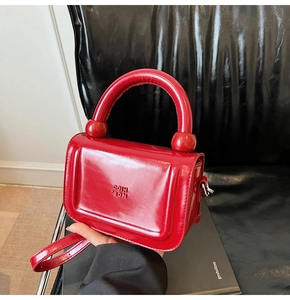 Vue détaillée du sac à main rouge brillant avec poignée épaisse et logo embossé