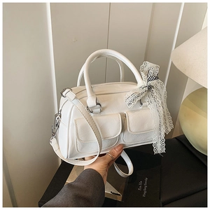 Détail du sac Boston blanc avec nœud en dentelle, cuir plissé et poches latérales