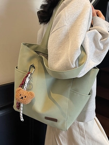 Minimalist light green canvas tote bag with brown bear pendant for student casual use