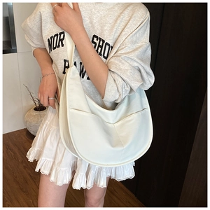Detail view of cream white crescent bag showing wide shoulder strap and front pocket detail