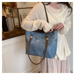 Detail of vintage denim blue tote bag with brown straps in a cozy cafe setting
