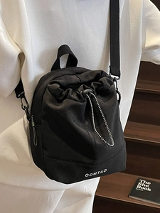 Japanese style black nylon drawstring crossbody bag with white logo on wooden stairs