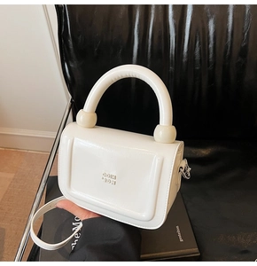 Détail d'un sac à main blanc en cuir ciré brillant avec logo embossé et finitions argent