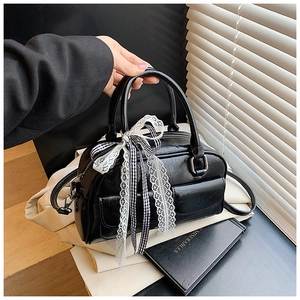 Détail du sac Boston en cuir plissé noir avec nœud à carreaux et bordure en dentelle