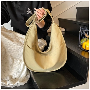 Detailed shot of a beige crescent hobo bag with adjustable strap on a dark staircase