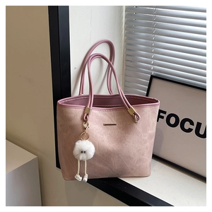 Detailed shot of pink faux leather tote bag with gold metal trim and white fluffy charm