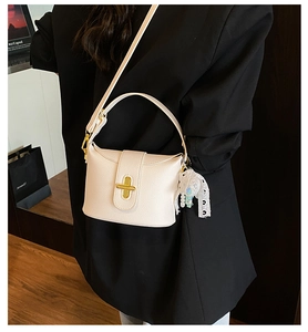 Detail of lychee textured leather bucket bag with golden cross lock and lace pearl charm