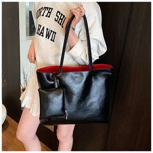 Close-up of black textured leather tote bag with red lining and matching small pouch
