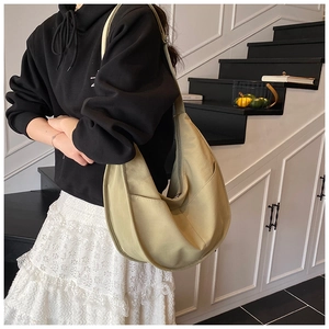 Detail view of sage green hobo crossbody bag with dual front pockets and wide shoulder strap