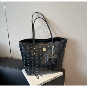 Detail of black printed tote bag featuring a leather texture and golden metal logo plaque