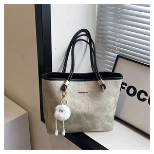 Detail of grey marble tote bag featuring gold hardware and a cute white plush monster charm